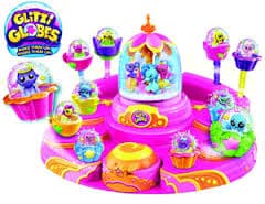 Colourful Glitzi Globes toy set with a pink and purple circular base, small animal figurines inside clear globes, and a larger central globe. The Glitzi Globes logo is on the top left. The set features cup-like seats and playful decorations.