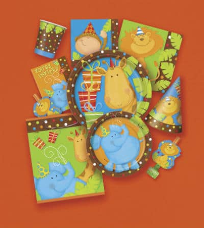 A collection of jungle-themed party supplies on an orange background, featuring plates, cups, hats, serviettes, and bags decorated with cartoon animals like giraffes, hippos, and monkeys wearing party hats, surrounded by presents and colourful patterns.