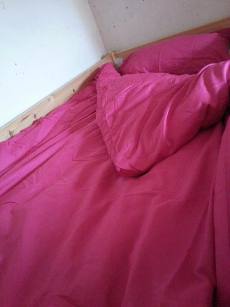 A pink bedspread on a bed.