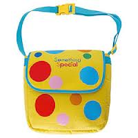 A small yellow shoulder bag with a blue strap and buckle, decorated with large red, blue, and pink spots. The flap has the words "Something Special" written in colourful letters.