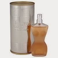 A torso-shaped perfume bottle with a soft peach colour, featuring a silver spray nozzle, stands next to a silver, cylindrical metal canister with embossed text. The overall design is elegant and feminine.