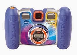 A colourful VTech Kidizoom digital camera with blue handles, orange shutter button, and silver front. The lens is in the centre, surrounded by a colourful circular design. The camera features two viewfinders and playful, vibrant patterns.