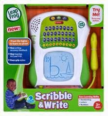 A LeapFrog Scribble & Write toy in its packaging. The device has a green and white body with a letter keypad, speaker, and a blue drawing screen showing childlike writing. A yellow stylus is attached. The box features a smiling child and colourful product details.