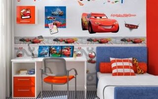 A children’s bedroom decorated with Disney Cars theme: Cars character stickers on the wall, a white desk with red drawers, an orange chair, toy cars, and a blue-and-white bed with orange, white, and chequered pillows. The floor has a blue chequered pattern.