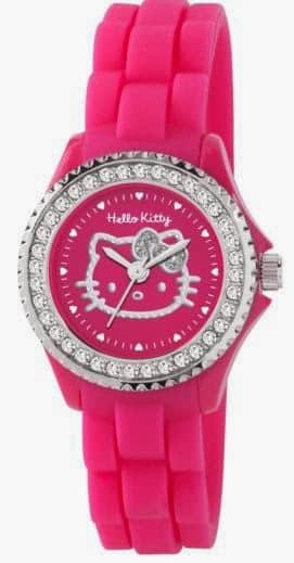 A bright pink Hello Kitty wristwatch with a silicone strap, rhinestone-studded silver bezel, and a pink face featuring Hello Kitty’s white outline and small white heart markers in place of numbers. The hour and minute hands are also silver.