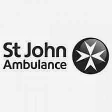 Black and white St John Ambulance logo. The text "St John Ambulance" appears on the left in a modern font. To the right is a circular emblem featuring a white eight-pointed Maltese cross on a black background.