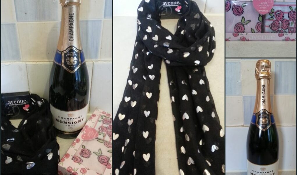 A collage shows: a bottle of Monsigny champagne, a black scarf with white hearts, a pink floral box, and the scarf draped separately. Each item appears individually and grouped, suggesting a themed gift set.
