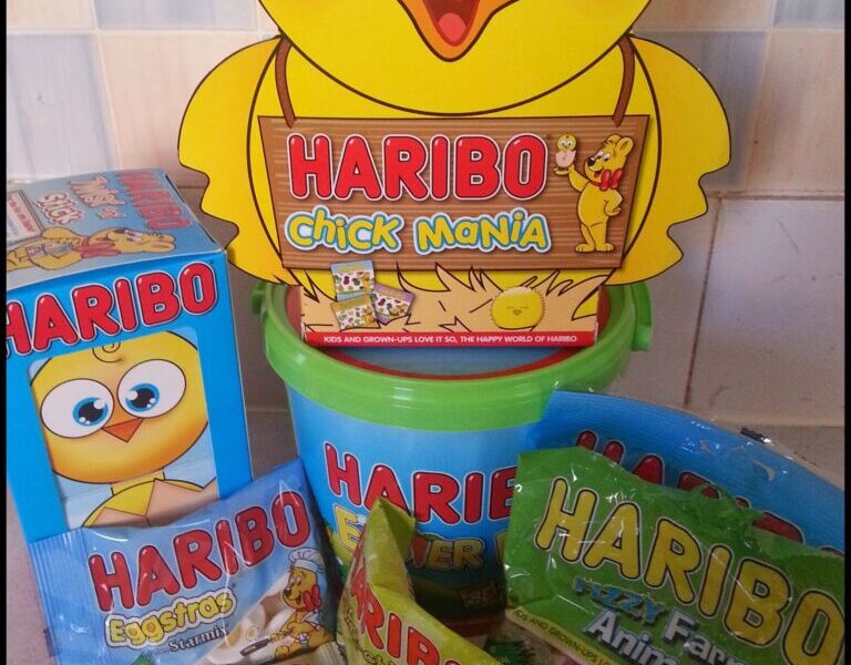 A collection of Haribo sweets with Easter-themed packaging, including a large yellow chick-shaped box labelled "Chick Mania," a green bucket, a blue box of "Eggs," and three packets of gummy sweets labelled "Jelly Bunnies," "Funny Mix," and "Farm Animals.