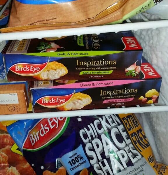 A freezer drawer filled with Birds Eye frozen foods, including two boxes of Inspirations meals (Garlic & Herb, and Cheese & Ham sauces) and a bag of Chicken Space Shapes. Other frozen items are partially visible in the background.