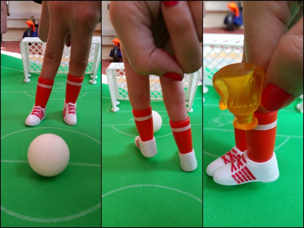 Three-panel image shows fingers wearing tiny red and white football boots and socks, posed as legs kicking a white football on a green pitch with toy goals. In the last panel, the fingers hold a small yellow trophy. The fingers have red nail varnish.