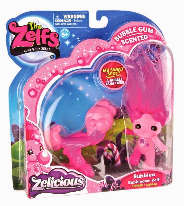 A packaged pink toy figure called Bubblee, the Bubblegum Zelf, with long, bright pink hair styled upwards. The packaging is colourful with heart and star designs, labelled "Bubble gum scented" and "Zelicious." For ages 5+ with a warning sign.
