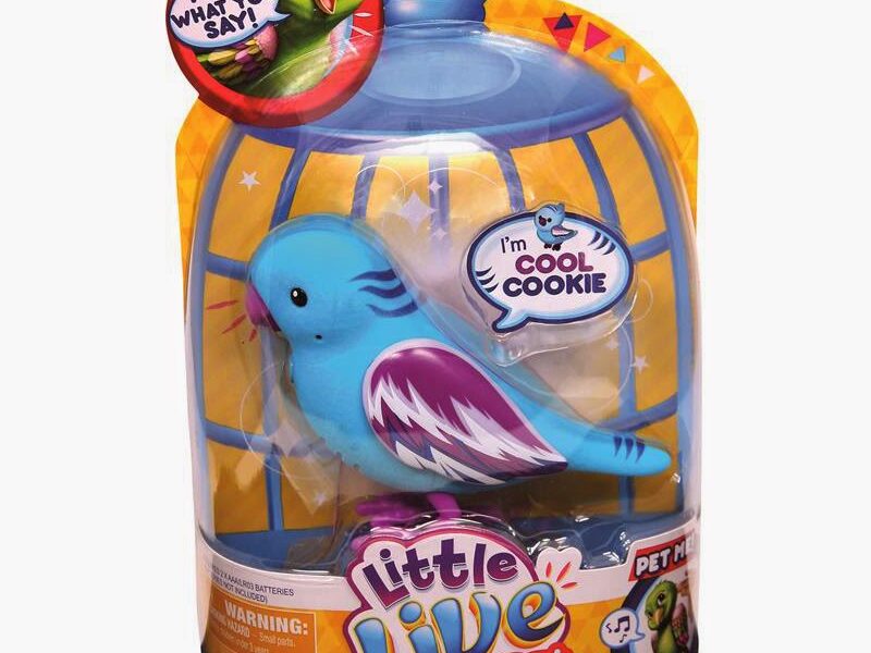 A toy blue bird with purple and white wings is enclosed in yellow and blue packaging shaped like a birdcage. The packaging reads “Little Live Pets” and features phrases like “I’m Cool Cookie,” “I tweet, I sing,” and “I say what you say!”.