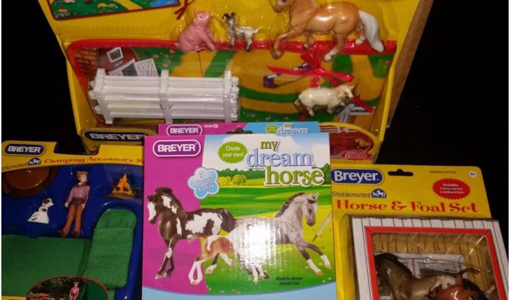 A collection of Breyer horse toy sets, including a "Hand Painted Horses" playset with horse figures and fences, a "Horse & Foal Set" in a yellow box, a "My Dream Horse Painting Kit," and a "Camping Accessories" set with a doll and camping kit.