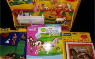 A collection of Breyer horse toy sets, including a "Hand Painted Horses" playset with horse figures and fences, a "Horse & Foal Set" in a yellow box, a "My Dream Horse Painting Kit," and a "Camping Accessories" set with a doll and camping kit.