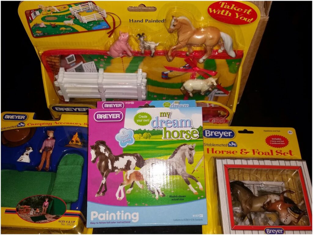 A collection of Breyer horse toys is displayed, including boxed sets with miniature horses, accessories like fences and bags, a "my dream horse" painting kit, a horse and foal set, and a camping accessory set with a small dog and tent.