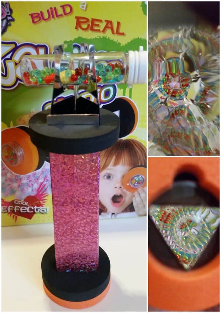 A pink, glittery kaleidoscope stands upright in front of colourful packaging. Close-ups on the right show colourful beads and geometric patterns seen through the lens. The box behind features a surprised child and the words “Build a Real Kaleidoscope”.