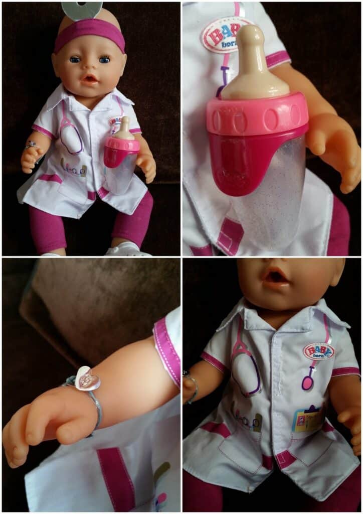 A baby doll dressed as a doctor in a white coat with pink trim, wearing a head mirror. It has a pink stethoscope print, name tag, and bracelet. The doll holds a pink baby bottle, and close-ups show its bracelet and outfit details.