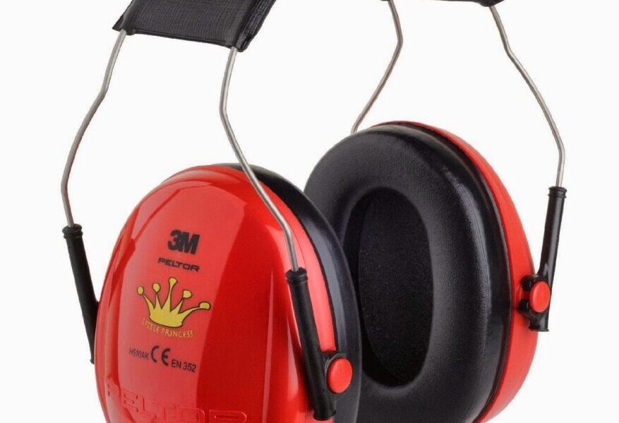 A pair of red 3M ear defenders with black cushioned ear pads and a black padded headband. The ear defenders feature a yellow crown design and certification markings on the side. The metal frame connects the ear cups to the headband.