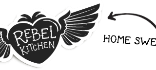 A black heart with white wings features the words “Rebel Kitchen” in bold white letters. An arrow points to the right with the phrase “Home Sweet Home” written in a playful, handwritten font. The background is light grey.