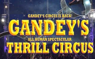 A circus performer runs inside a large metal wheel high above a ring, under a starry big top. Bold yellow and red text reads: “GANDEY’S CIRCUS IS BACK! GANDEY'S ALL HUMAN SPECTACULAR THRILL CIRCUS.” Spotlights shine on the wheel and crowd.