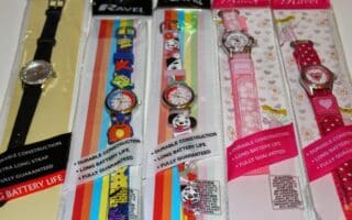 Five packaged wristwatches are displayed side by side. The first has a plain black strap, whilst the others feature colourful designs with animals, pandas, kittens, and unicorns. Each package highlights features like durability and long battery life.