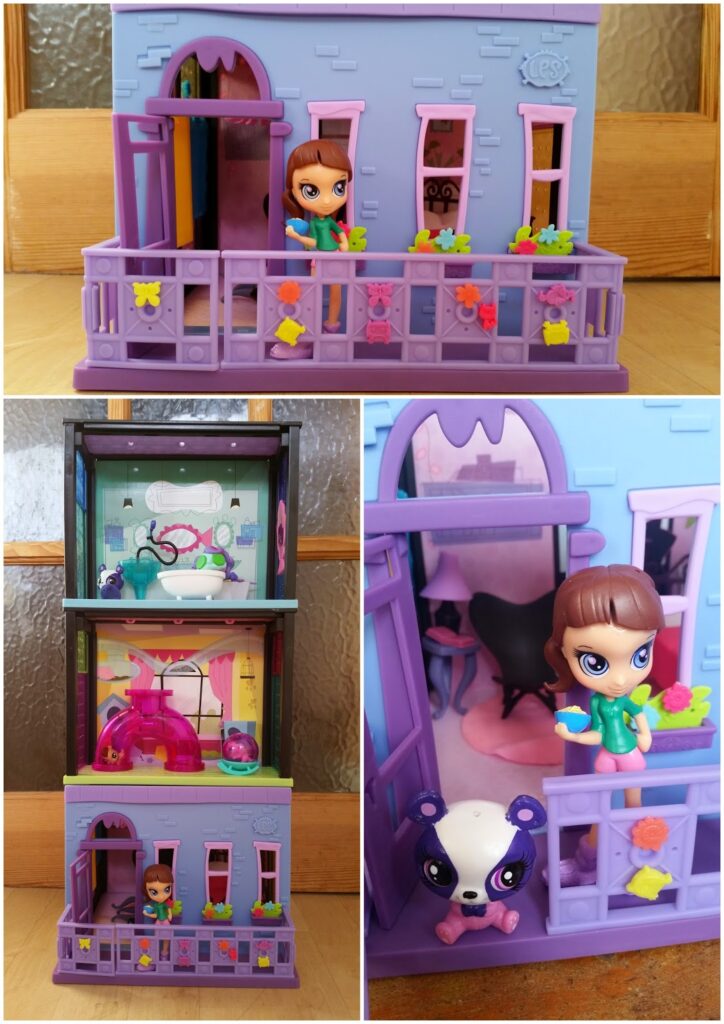 A purple and blue toy dolls' house stands on a wooden surface. The house has a balcony decorated with flower shapes. A small brown-haired doll in a green outfit holds flowers. There’s a panda figurine and colourful rooms inside the dolls' house.