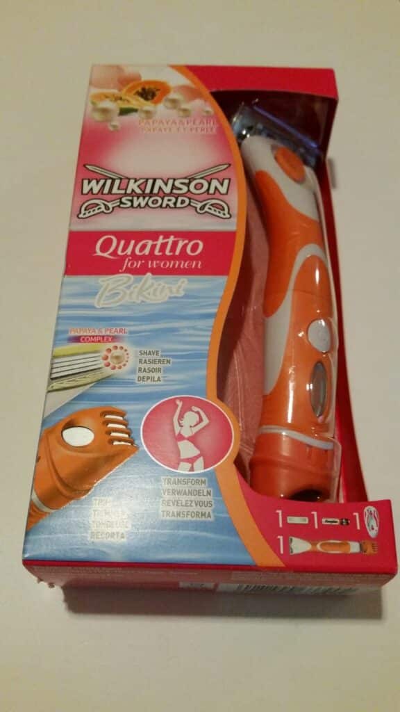A pink and orange Wilkinson Sword Quattro for Women Bikini razor pack is shown. The packaging mentions "Papaya & Pearl Complex," features an image of the razor, and highlights dual-purpose shaving and bikini trimming functions with product illustrations.