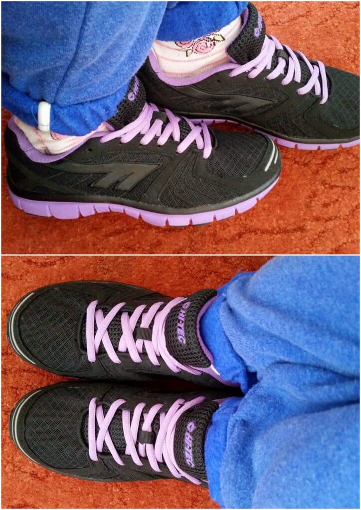 A person wearing blue fleece trousers, pink patterned socks, and black trainers with purple soles and laces stands on an orange carpet. The photo is split: the top shows a side view, the bottom shows the shoes from above.