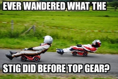 Two people in racing suits and helmets drive tiny toy cars at high speed on a tarmacked rural road. Bold white text at the top and bottom says: "Ever wondered what the Stig did before Top Gear?".