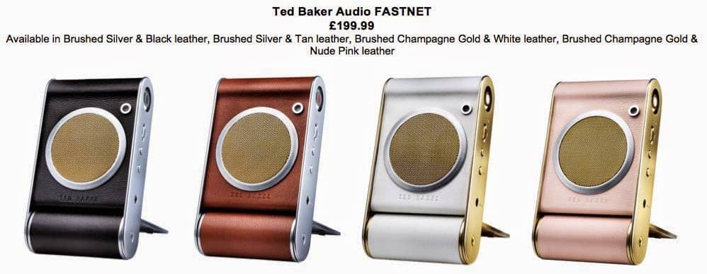 Four compact wireless speakers, each with a leather finish and metallic accents, are displayed in black, tan, white, and nude pink colours. Each speaker has a round golden grille, control buttons on the side, and a folding stand with “Ted Baker Audio” branding.