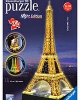 Box of a Ravensburger 3D puzzle, “Night Edition” Eiffel Tower, showing a lit-up model of the Eiffel Tower against a night sky. The box says “216 pieces” and features small images of the puzzle glowing in different colours.