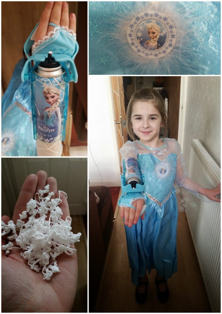 A girl wearing a blue Elsa costume from Frozen stands indoors, smiling and holding up her arm. Attached to her wrist is a can spraying artificial snow. Close-ups show the can, a snowflake pattern on the dress, and fake snow in her hand.