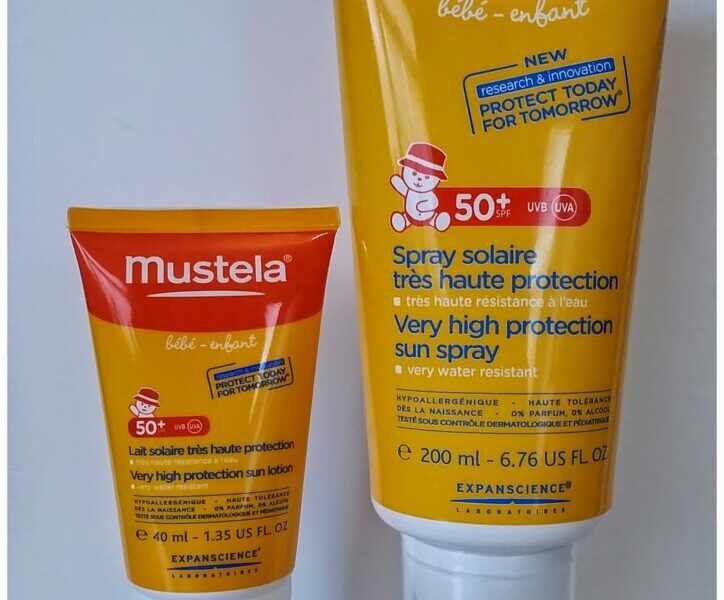 Two tubes of Mustela suncream are standing upright against a plain background. The smaller tube is 40ml and the larger is 200ml. Both feature red and yellow packaging, SPF 50+ labels, and text indicating "very high protection" for babies and children.
