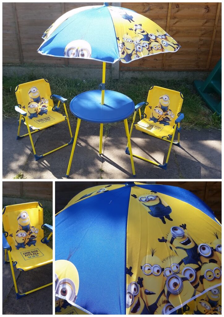 A children’s outdoor table set featuring two yellow chairs and a round table with a matching parasol, all decorated with Minions characters from "Despicable Me." The set is placed on a patio against a wooden fence. Two close-ups show chair and parasol details.