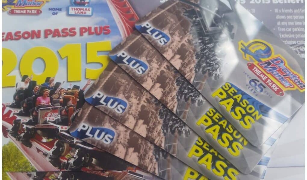 Several Drayton Manor Theme Park 2015 season pass cards fan out across a brochure. The brochure features the Drayton Manor logo, "2015 Season Pass Plus," and an image of people riding a rollercoaster. The cards display the park logo and "PLUS SEASON PASS" text.