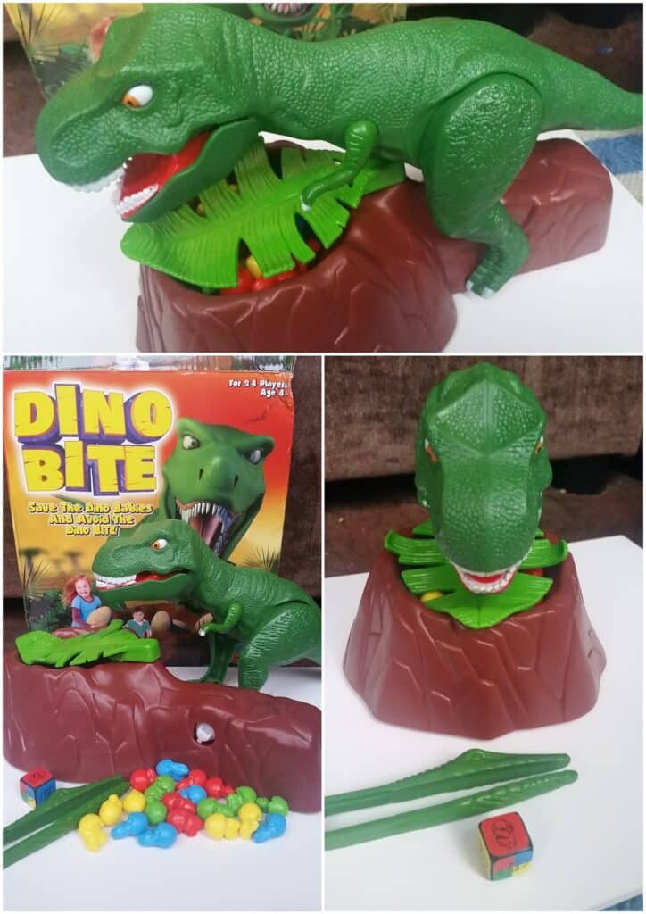 A green plastic T-rex toy with an open mouth stands on a brown rocky base. The game includes colourful plastic eggs, green tweezers, and a die. The box reads "Dino Bite" and shows a cartoon dinosaur about to eat a trapped figure.