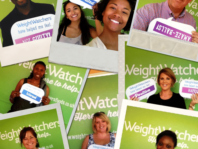 A collage of eight smiling adults of various ages and ethnicities stands in front of a green WeightWatchers backdrop, each holding signs with positive words like “NOT GUILTY!”, “AMAZE-BALLS!”, “HAPPY!!!”, “POSITIVE”, and “BRILLIANT!!!”.