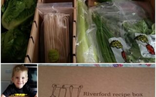 A Riverford recipe box contains fresh vegetables, wooden skewers, and recipe cards. The box is labelled "Riverford recipe box quick." A child smiles near the open box, which is compartmentalised for different ingredients.