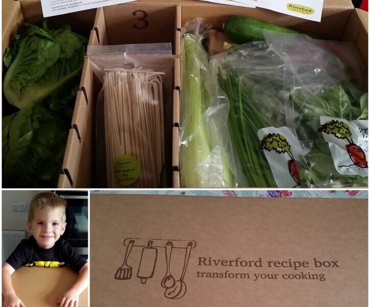 A Riverford recipe box contains fresh vegetables, wooden skewers, and recipe cards. The box is labelled "Riverford recipe box quick." A child smiles near the open box, which is compartmentalised for different ingredients.
