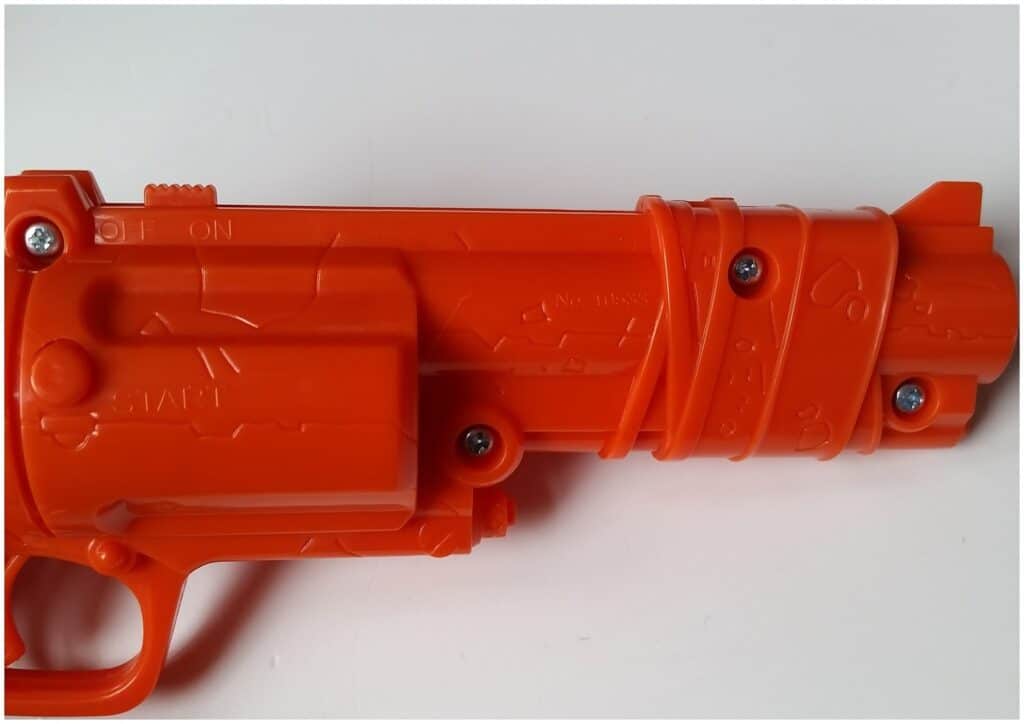 A close-up of an orange plastic toy gun showing the barrel and part of the handle. The toy features moulded details, screws, and "ON/OFF" and "START" labels, with a matt finish against a plain white background.