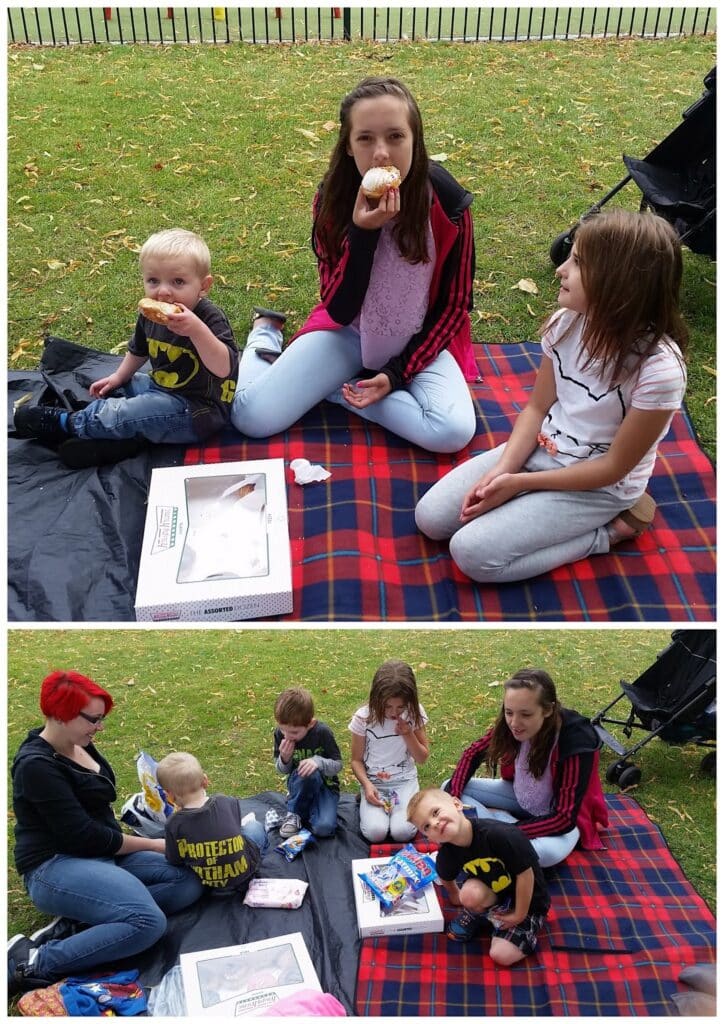 Two photos: In both, children and an adult have a picnic on a red checked blanket outdoors. They eat snacks and doughnuts from a box. In the first image, three children sit together; in the second, an adult with red hair joins them. Grass and trees are visible.