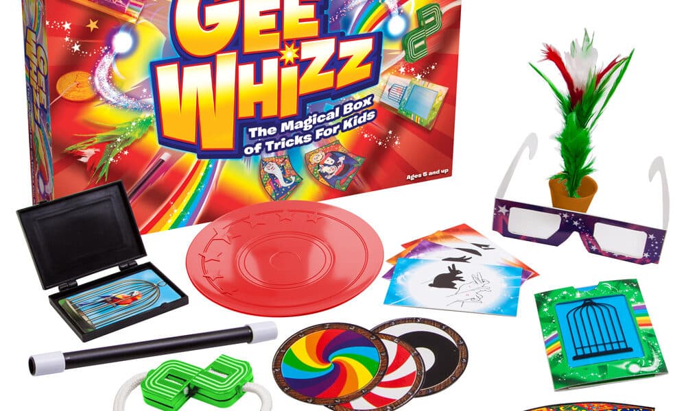 A colourful magic trick set called “Gee Whizz: The Magical Box of Tricks For Kids” is displayed. The box is bright with rainbows and stars. Various magic props are arranged in front: cards, rings, rope, wand, glasses, coins, and other playful accessories.