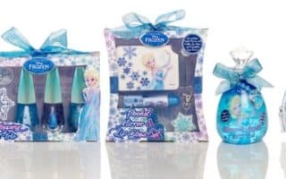 A line-up of Frozen-themed beauty products features Elsa and snowflake designs. Items include lip balms, nail varnish, perfume, and a zippered pouch labelled "Queen of Snow," all in blue, purple, and white packaging with ribbon accents.