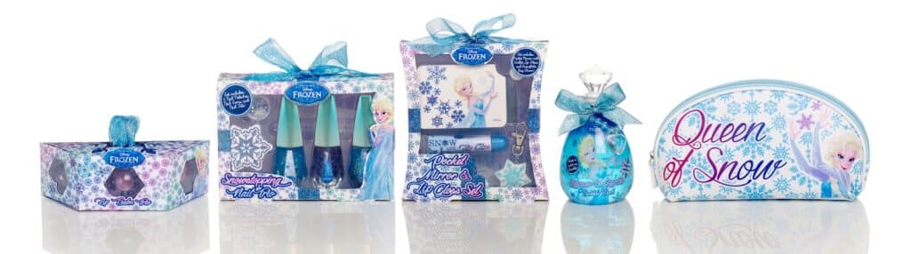 A set of Disney Frozen-themed beauty products including bath fizzers, nail varnish, lip glosses, perfume, and a cosmetic bag with "Queen of Snow" written on it, all decorated with images of Elsa and snowflakes in blue, white, and purple tones.