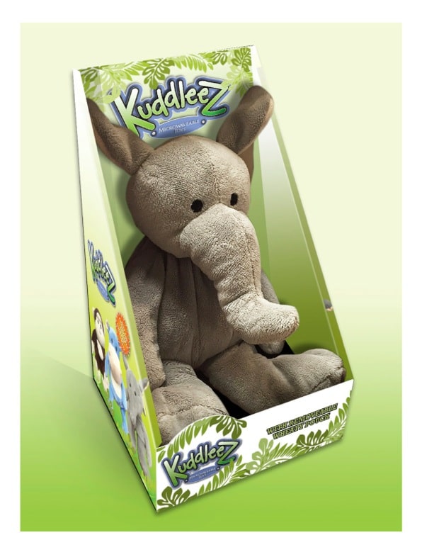 A soft, grey plush elephant with floppy ears and a long trunk sits inside green and white packaging labelled “Kuddlez.” Cartoon animal illustrations and leafy graphics decorate the box. The background is a light green gradient.