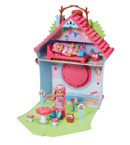 A colourful doll’s house shaped like a birdhouse with a pink roof and green garden. A doll sits outside near red toadstools, while another doll rests in a bed on the top floor. Toy owls and whimsical decorations are scattered throughout the playset.