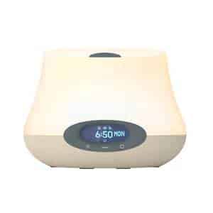 A cream-coloured digital alarm clock with a curved top and an oval blue display showing the time 6:50 and the day MON. The clock face has small buttons below the screen and a button on top. The background is plain white.