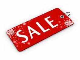 A red sale label with the word “SALE” in bold white letters, decorated with white snowflakes and dots, suggesting a winter or holiday promotion. The label has a black string looped through a hole in the corner.