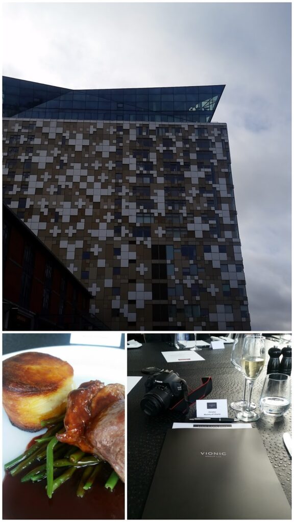 A collage: Top shows a modern, angular building with a mosaic façade under a cloudy sky. Bottom left is a plated meal with sliced meat, green beans, and roast potatoes. Bottom right shows a table with a black folder, camera, champagne, and glasses.