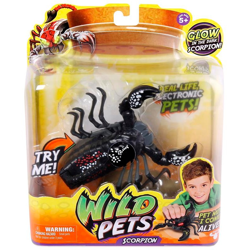 A packaged Wild Pets electronic scorpion toy with black body, red and white details, and glow-in-the-dark feature. The packaging shows a smiling child holding the toy and includes text such as “Try Me!” and “Real Life Electronic Pets!” for ages 5 and over.